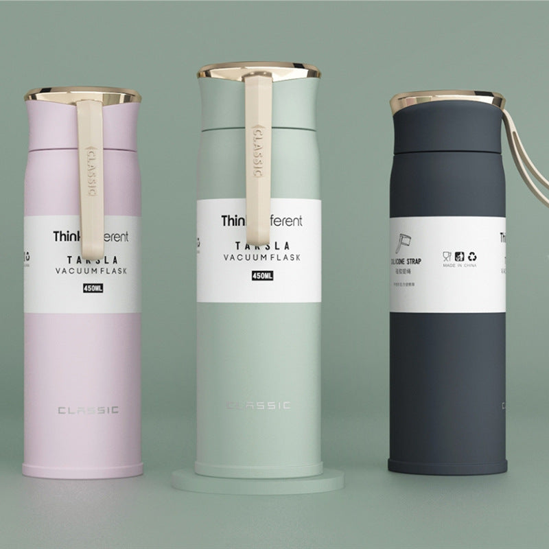 Three vacuum flasks in different colors on a gray background