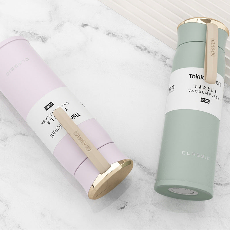 Two vacuum flasks, one pink and one green, on a marble surface.