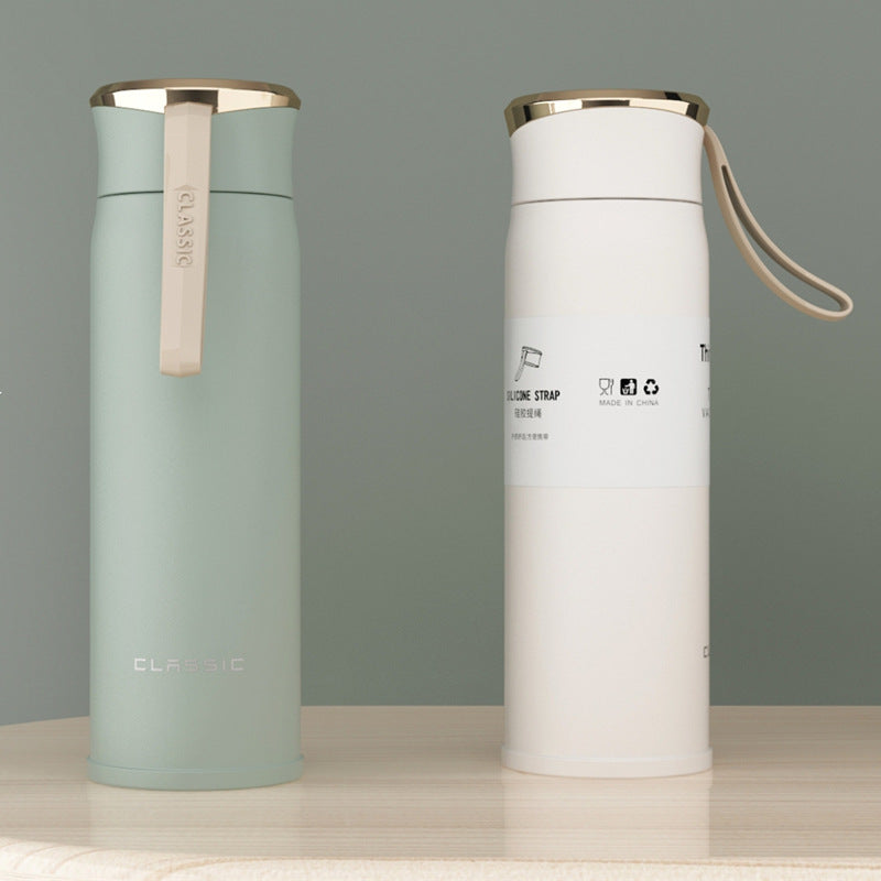 Two insulated bottles, one green and one white, on a gray background.