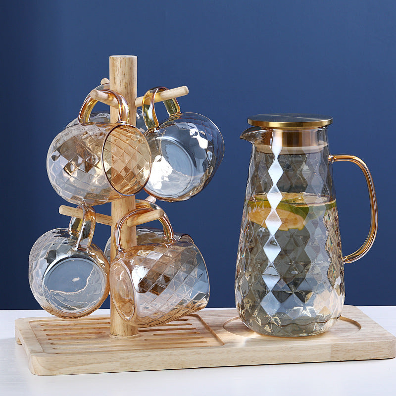 Set of glass cups with a wooden stand and a glass carafe on a blue background