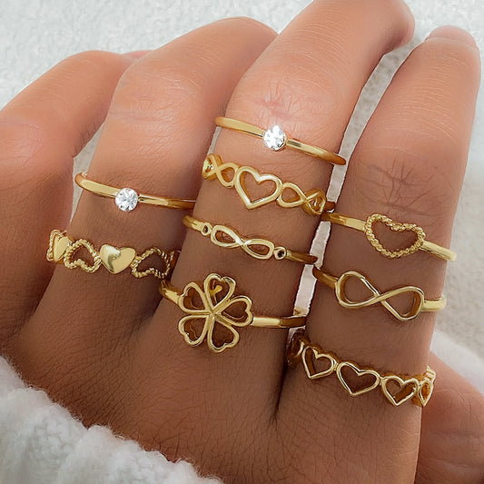 Gold rings with various designs on a hand against a neutral background