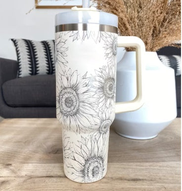 White tumbler with black floral design on a wooden table